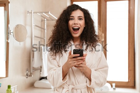 Cheerful young lady dressed in pajama listening music. Stock photo © deandrobot