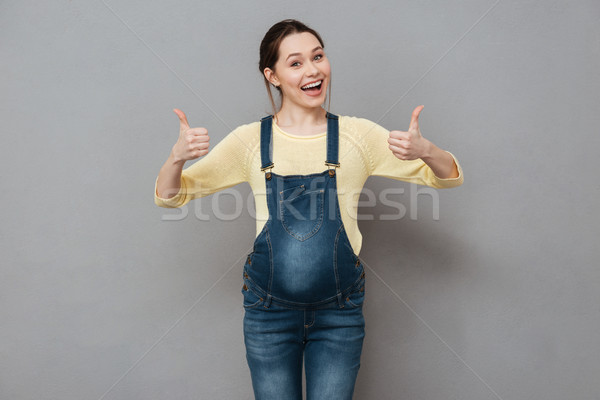 Pretty smiling pregnant lady showing thumbs up gesture. Stock photo © deandrobot