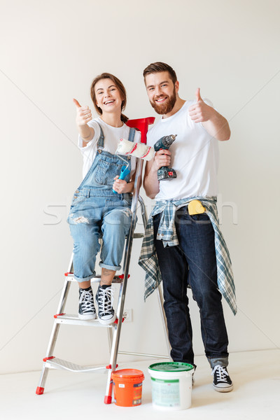 Happy lovers showing thumb up while making repair Stock photo © deandrobot
