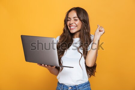 Image of amazing businesswoman holding silver laptop and pointin Stock photo © deandrobot