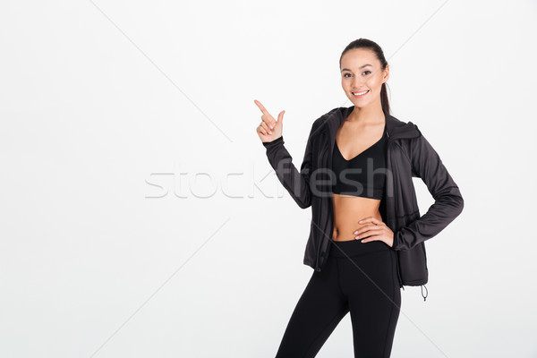 Cheerful young sports lady pointing to copyspace. Stock photo © deandrobot