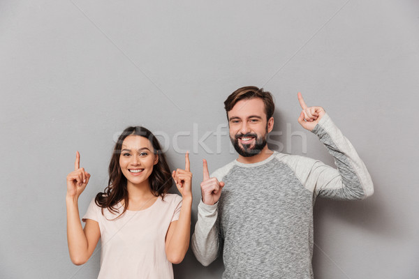 Stock photo: Portrait of a cheerful young couple pointing fingers up