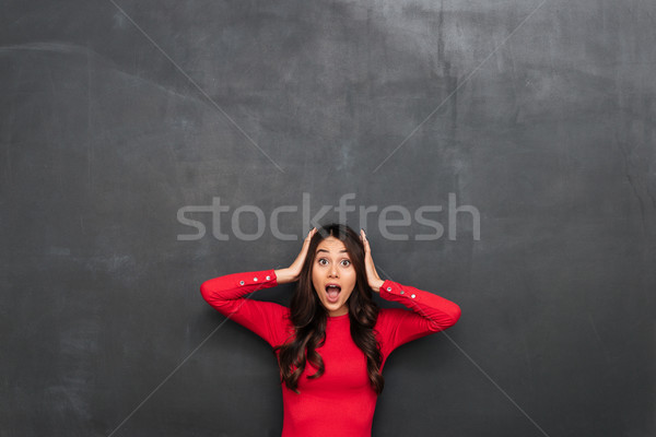 Picture of shocked brunette woman in red blouse holding head Stock photo © deandrobot