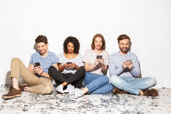 Group of happy multiracial people sitting on a floor Stock photo © deandrobot