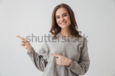 Souriant brunette femme chandail pointant loin Photo stock © deandrobot