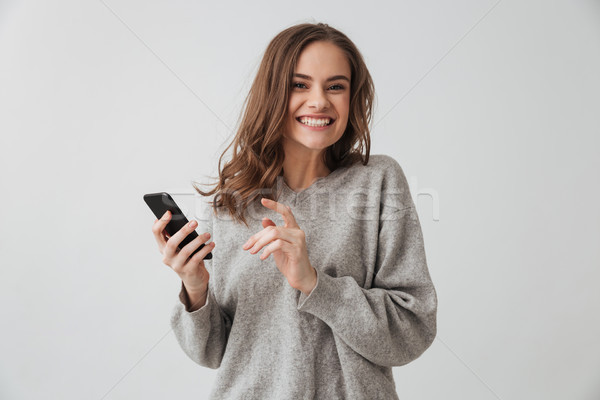 Mosolyog barna hajú nő pulóver tart okostelefon Stock fotó © deandrobot