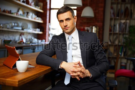 Confident businessman in formal cloths drinking coffee and reading news in the kitchen Stock photo © deandrobot