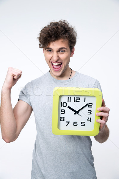Happy man holding clock with arms raised over gray background Stock photo © deandrobot