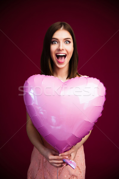 Surprised woman holding heart shaped balloon Stock photo © deandrobot