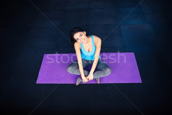 Happy fit woman sitting on yoga mat  Stock photo © deandrobot