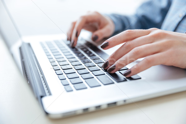 Hands of woman in blue shirt typing on laptop keyboard Stock photo © deandrobot