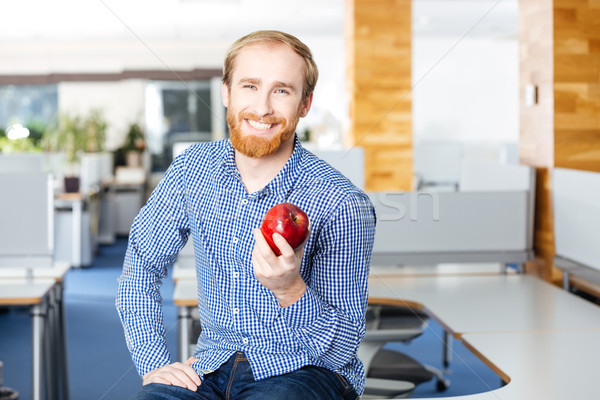 Happy businessman siting in office and holding red apple  Stock photo © deandrobot