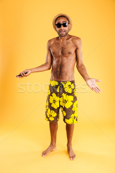 Confused young handsome african man talking on cell phone Stock photo © deandrobot