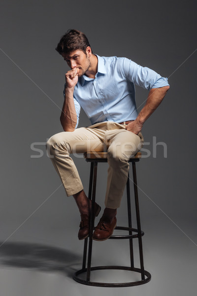 Attractive young man in blue shirt sitting on chair Stock photo © deandrobot