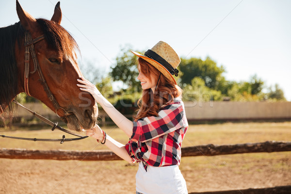 Smiling woman cowgirl taking care of her horse on farm Stock photo © deandrobot