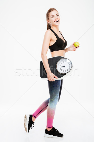 Stock photo: Happy fitness woman holding weighing machine and green apple