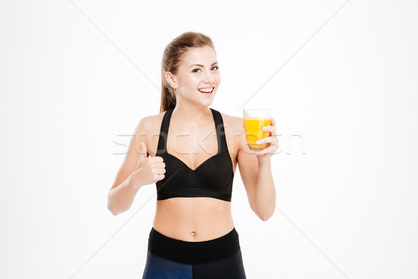 Sportswoman holding orange juice glass and showing thumbs up gesture Stock photo © deandrobot