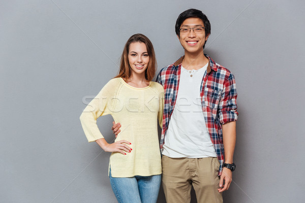 Stock photo: Smiling young interracial couple hugging and looking at camera