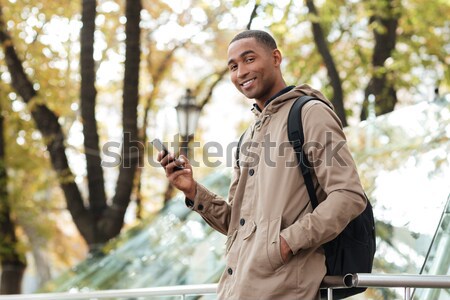 Young african man with backpack talking on phone at street Stock photo © deandrobot