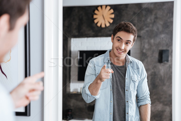 Lächelnd junger Mann Hinweis Finger Spiegel Reflexion Stock foto © deandrobot
