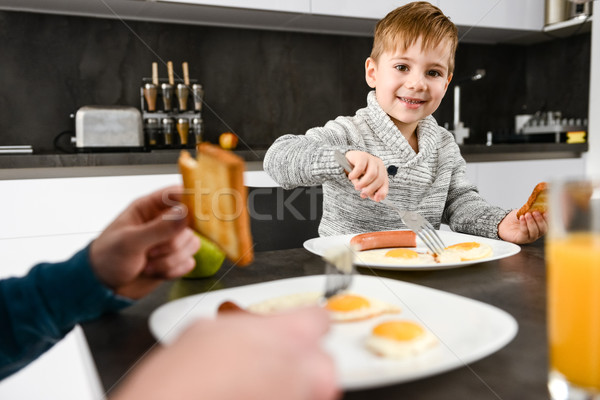 Happy little boy eating at kitchen with his father. Stock photo © deandrobot