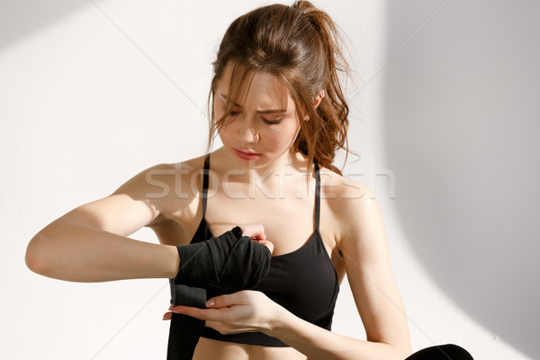 Serious woman wrapping hands with black boxing bandage Stock photo © deandrobot