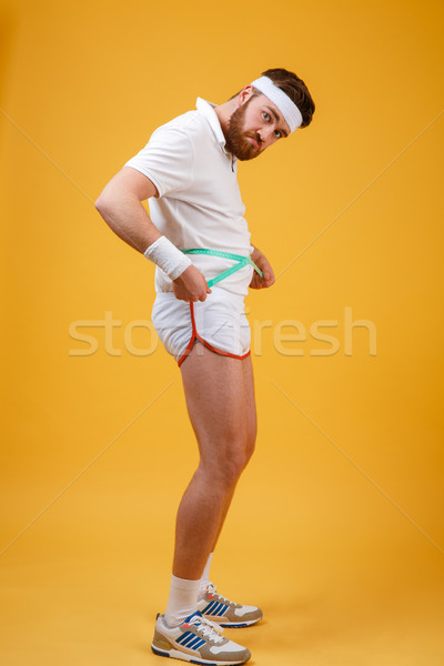 Portrait of a sad unsatisfied fitness man measuring his body Stock photo © deandrobot