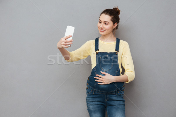 Portrait of a pregnant woman making selfie photo on smartphone Stock photo © deandrobot