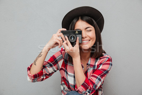 Stock photo: Funny young asian woman isolated over grey wall holding camera.