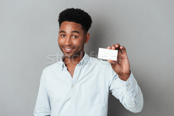 Smiling young afro american guy holding blank business card Stock photo © deandrobot