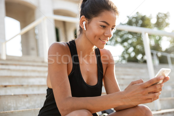 Portré mosolyog fitnessz lány fülhallgató ül Stock fotó © deandrobot
