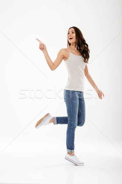 Full length image of Happy woman pointing and looking away Stock photo © deandrobot