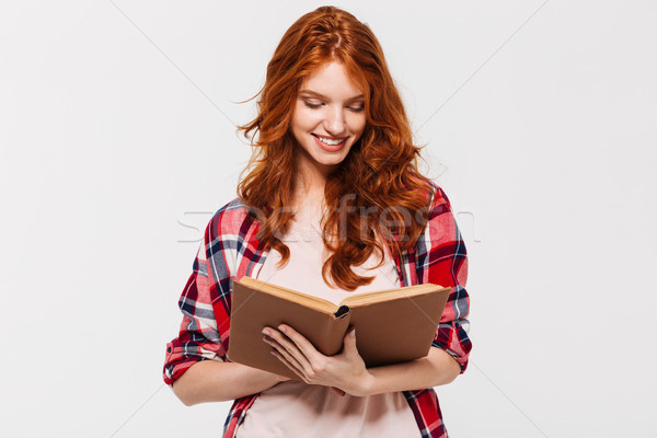 Smiling ginger woman in shirt holding and reading book Stock photo © deandrobot