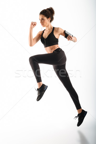 Full length image of Concentrated curly brunette fitness woman running Stock photo © deandrobot