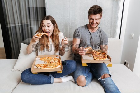 Happy young couple eating pizza and drinking beer Stock photo © deandrobot