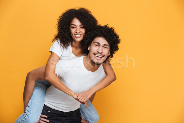 Portrait of a smiling african man carrying girlfriend Stock photo © deandrobot