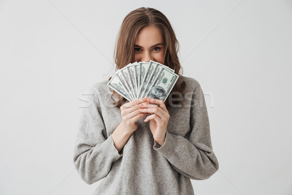Smiling sly brunette woman in sweater hiding behind money Stock photo © deandrobot