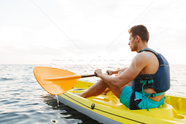 Handsome man kayaking on lake sea in boat. Stock photo © deandrobot