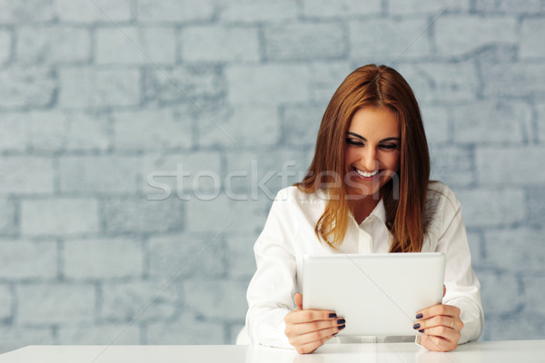 Laughing young businesswoman looking at tablet computer screen Stock photo © deandrobot