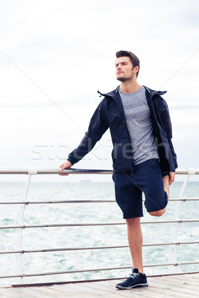 Handsome sportsman stretching legs outdoor Stock photo © deandrobot
