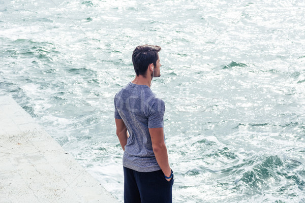 Man in sports wear standing near sea Stock photo © deandrobot