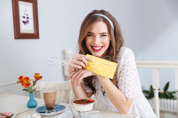 Cheeerful attractive woman drinking latte and eating dessert in cafe Stock photo © deandrobot