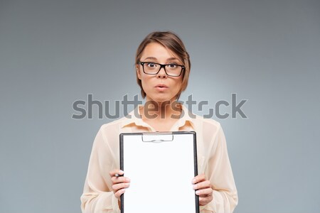 Teenage girl in glasses showing and pointing on blank clipboard Stock photo © deandrobot