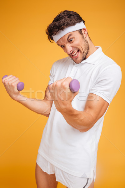 Fitness man doing exercises and lifting two heavy small dumbbells Stock photo © deandrobot