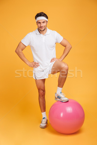 Young handsome sportsman with fitness ball holding hands on hips Stock photo © deandrobot