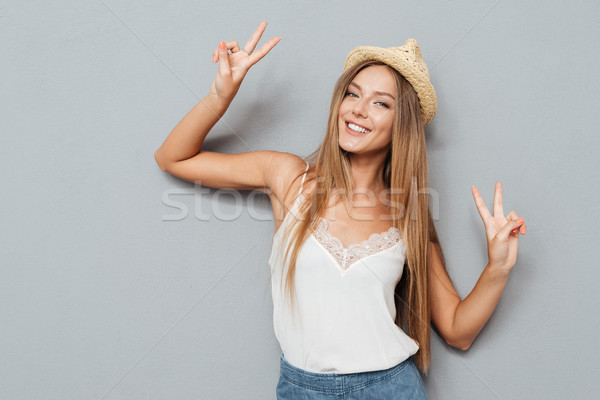 Portrait of a smiling woman in hat showing peace sign Stock photo © deandrobot