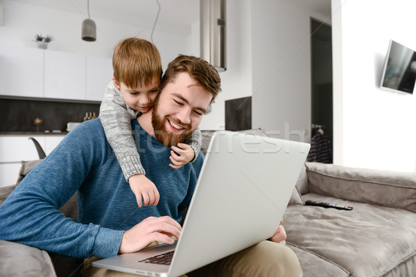 Cheerful young father with cute son using laptop Stock photo © deandrobot