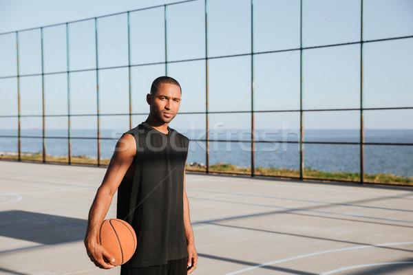 Young sportsman standing with basketball and looking at camera Stock photo © deandrobot
