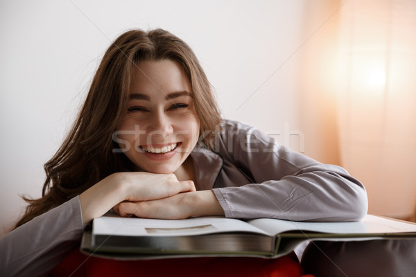Laughing woman lying on bag chair with book Stock photo © deandrobot