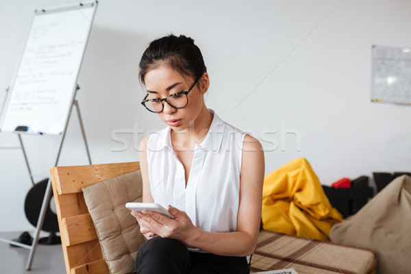 [[stock_photo]]: Concentré · asian · jeune · femme · séance · smartphone · verres